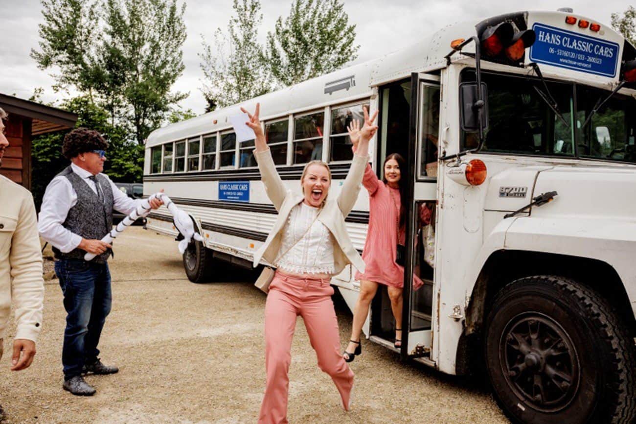 Blije mensen die uit een witte Amerikaanse schoolbus stappen