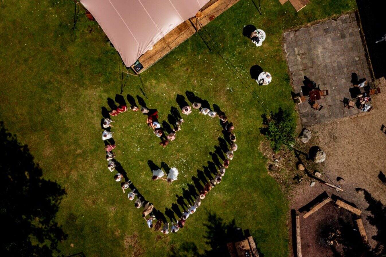 Bovenaanzicht getrouwd stel dat omringd wordt door bezoekers in de vorm van een hart
